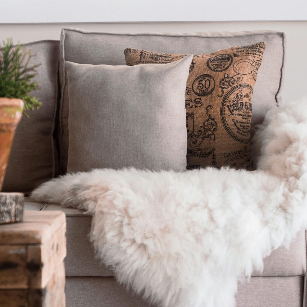 Warm and inviting living room with a focus on soft textures, featuring a sofa with fur throws and decorative pillows.