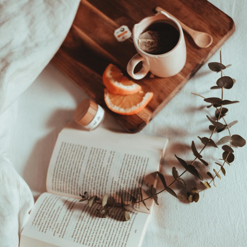 A cozy morning setup with a book, tea, and citrus slices creating a warm ambiance.